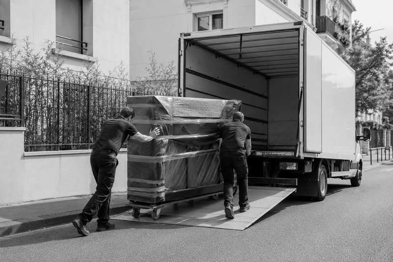 Déménageurs conduisant un piano droit emballé sur chariot vers le camion