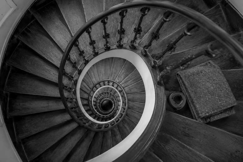 Escalier parisien en colimaçon vu en plongée, couverture de déménagement et sangle posées sur une marche