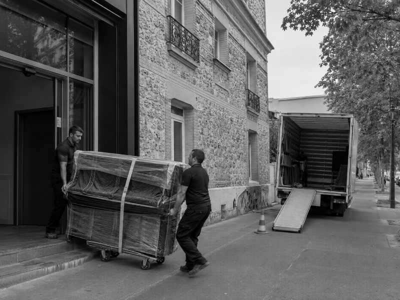 Sortie d’un piano droit emballé du hall d’un immeuble en meulière à Bourg-la-Reine (92)