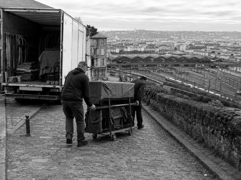 Descente d’un piano droit par une rue raide à Juvisy-sur-Orge (91), gare et faisceau de voies en contrebas