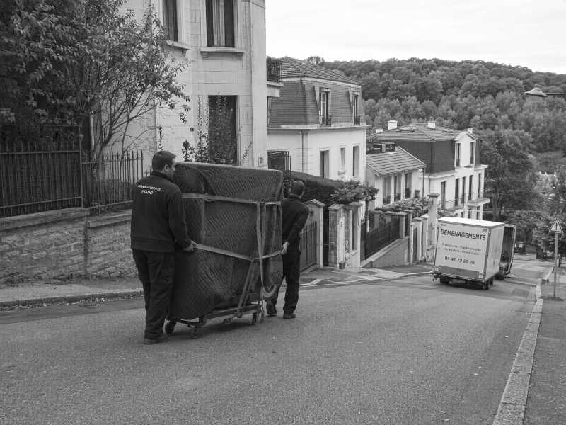 Descente d’un piano droit sur chariot dans une rue en pente d’un coteau à Meudon (92)