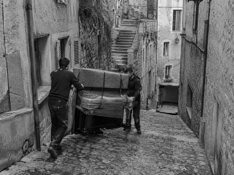 Portage d’un piano droit dans une ruelle pavée du centre historique de Pontoise (95)