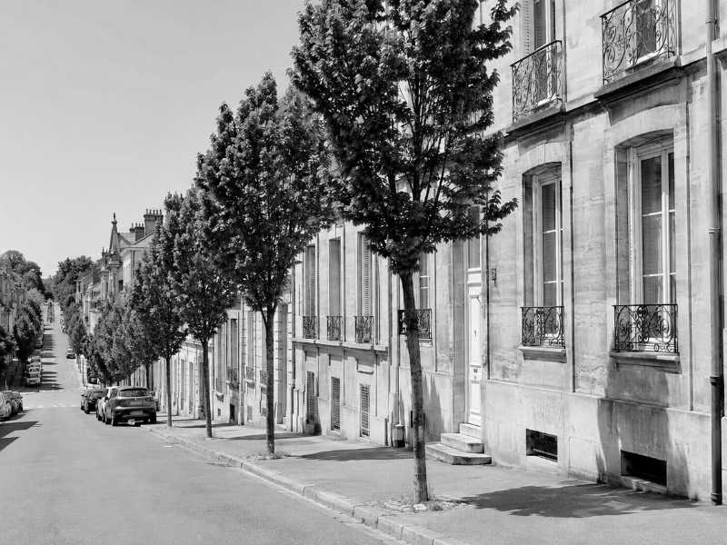 Rue en pente de Saint-Germain-en-Laye bordee d immeubles en pierre au stationnement limite
