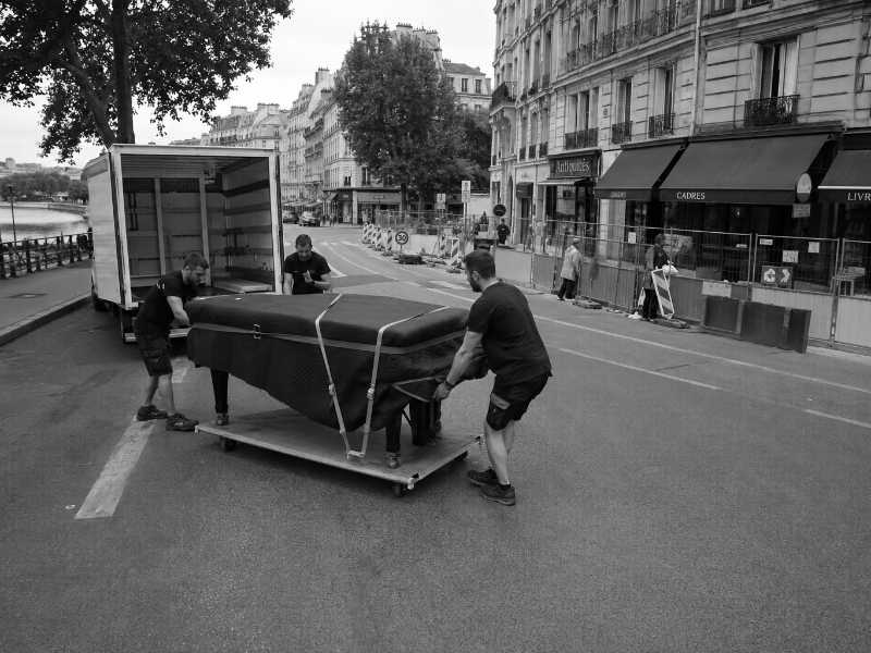 Piano à queue houssé déplacé sur une rue en pente à Sèvres (92), travaux de voirie en face