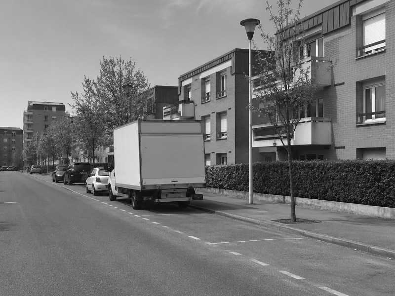 Rue plate de Trappes avec stationnement le long du trottoir pour le camion de demenagement de piano