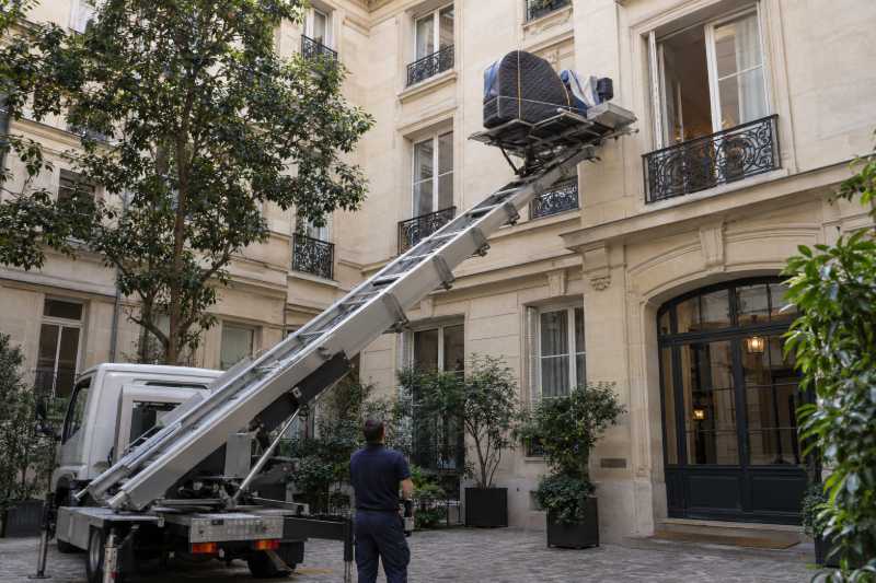 Piano à queue emballé hissé par un monte-meubles dans la cour intérieure d'un immeuble ancien