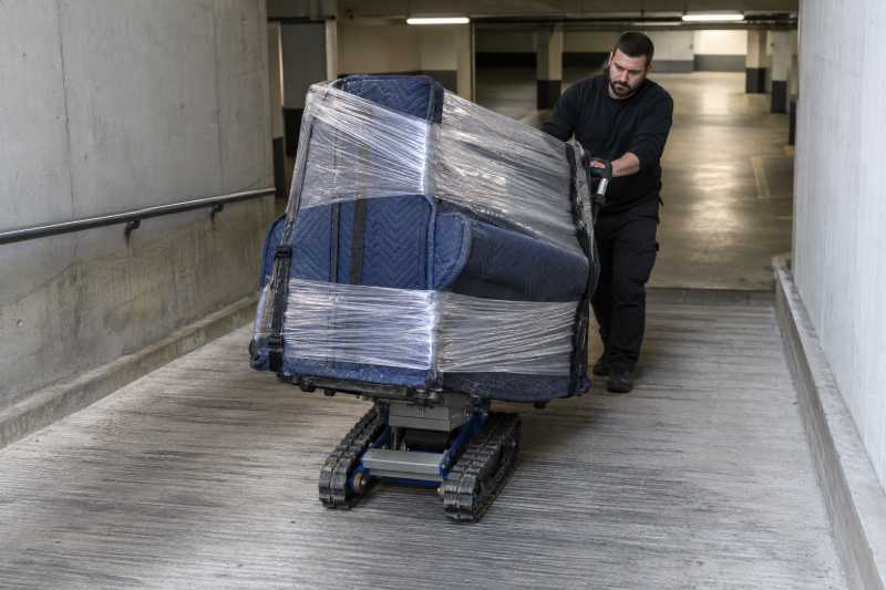 Piano droit emballé sur un diable chenillé électrique dans une rampe de garage, Chelles
