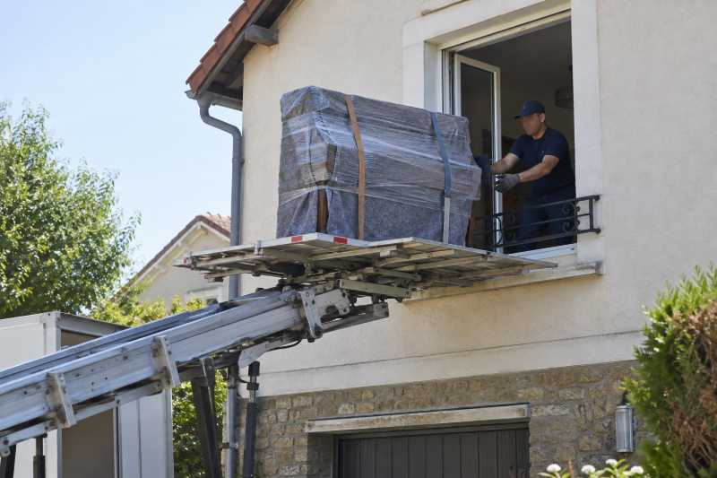 Piano droit emballé arrivant par monte-meubles à la fenêtre d'étage d'un pavillon, Orsay