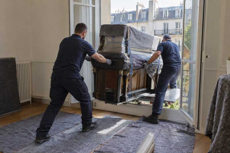 Déménageurs faisant entrer un piano droit par une fenêtre depuis un monte-meubles, Paris 19e