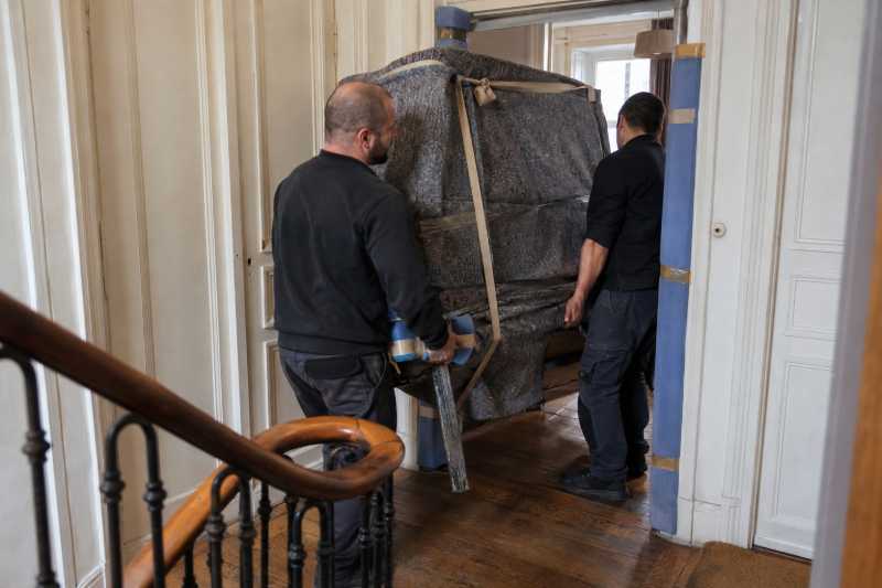 Deux déménageurs faisant passer un piano emballé sur le côté par une porte étroite, Thiais