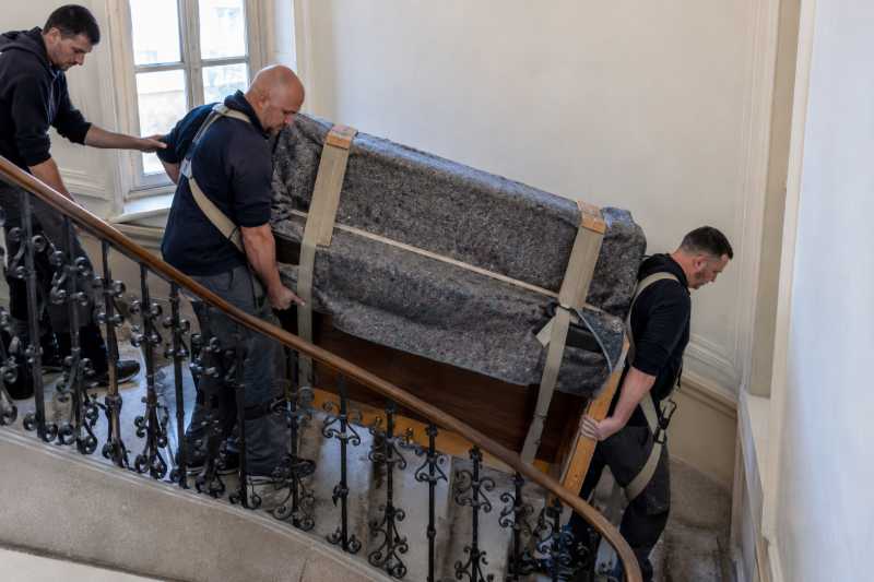 Deux déménageurs au harnais descendant un piano droit emballé dans un escalier d'immeuble, Choisy-le-Roi